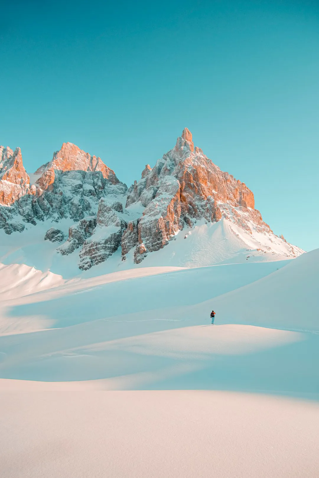 Hiker crossing a snow-covered slope high in the mountains